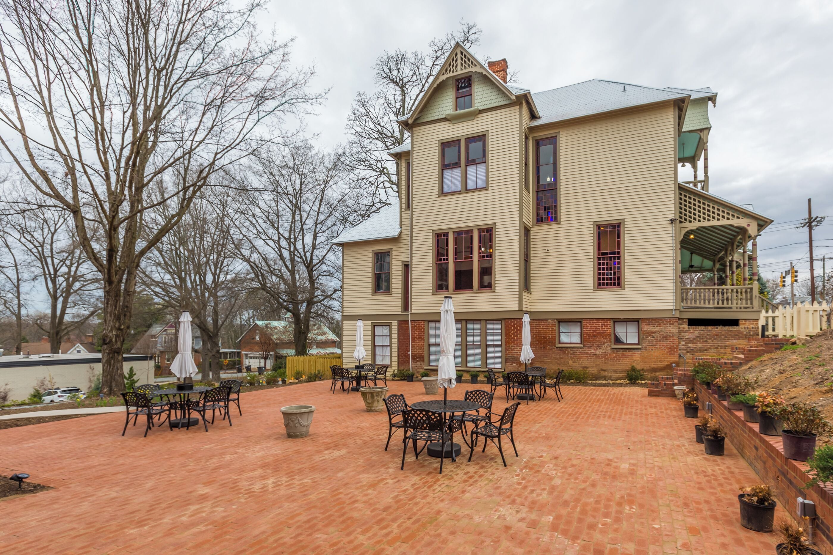 A two-story building with a patio area featuring outdoor seating and umbrellas.
