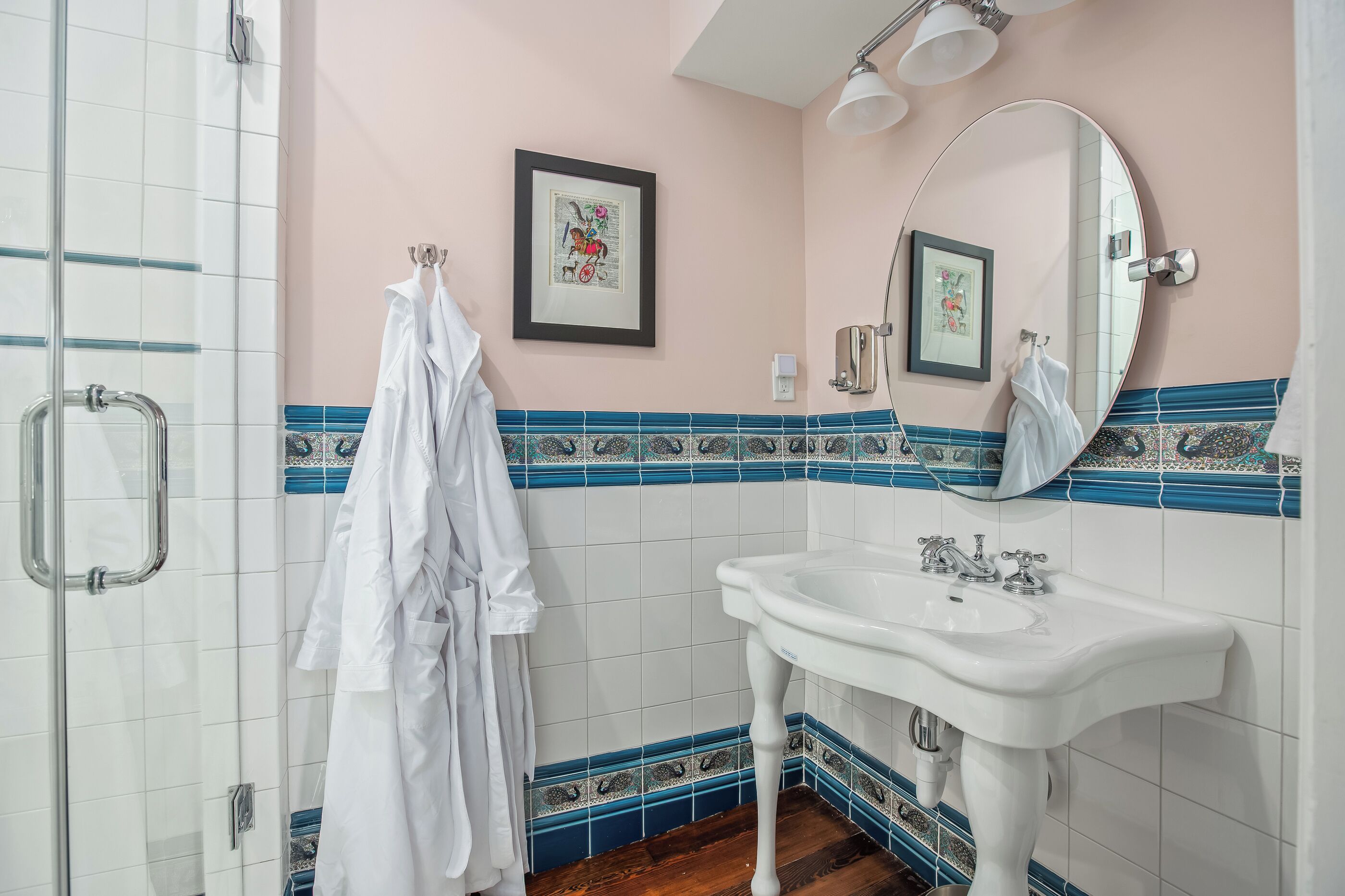 A bathroom with a white sink, a mirror, and a framed picture on the wall.
