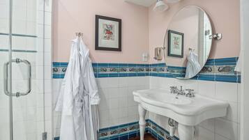 A bathroom with a white sink, a mirror, and a framed picture on the wall.