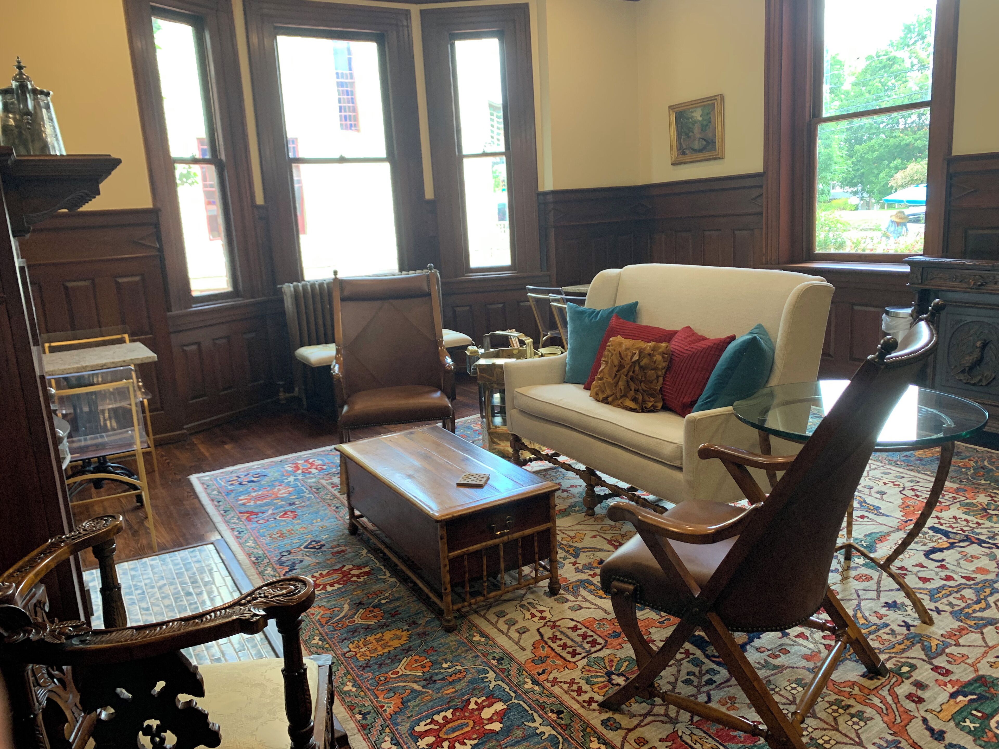 A traditional living room with a sofa, armchairs, a coffee table, and a glass table.