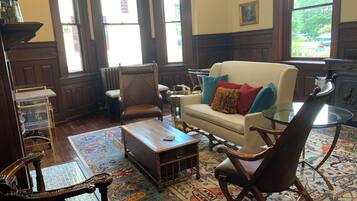 A traditional living room with a sofa, armchairs, a coffee table, and a glass table.