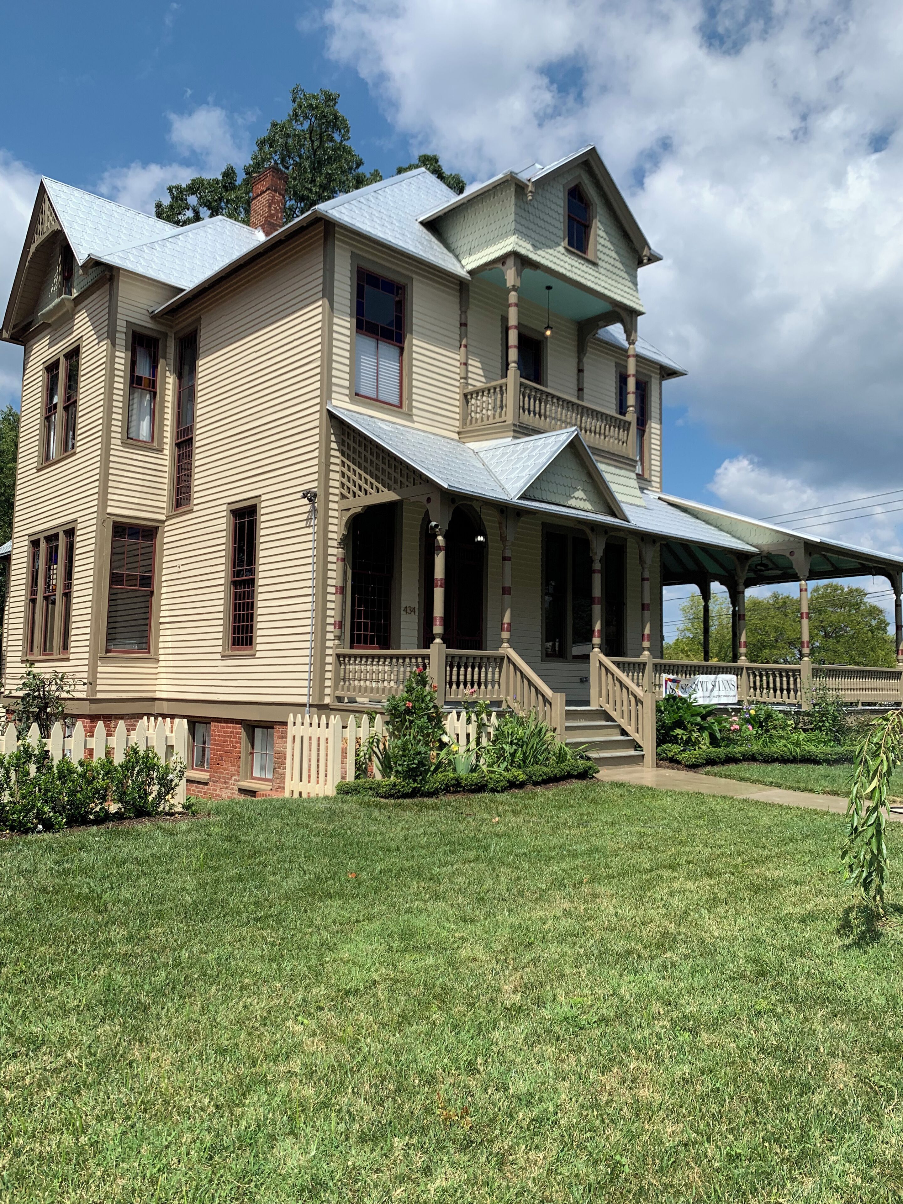 A two-story house with a porch, a covered front porch area, and a brick chimney.