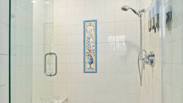 Een moderne douche met een glazen cabine, een wandspiegel en een decoratief betegeld paneel.