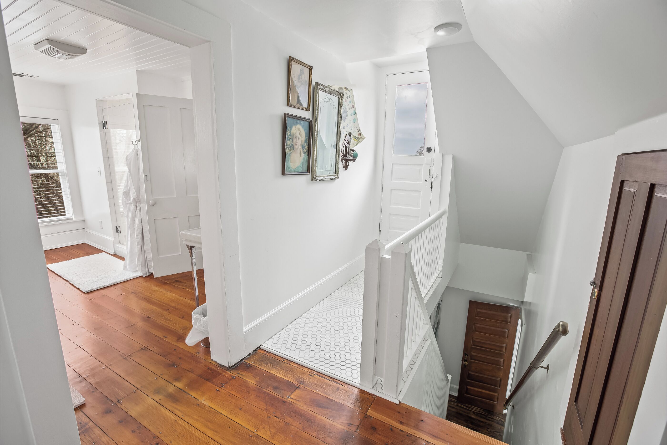 A staircase with a wooden handrail and white walls.