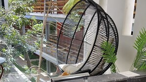 A modern outdoor seating area with a black wicker chair, a marble sink with a faucet, and a water spout. - Departamento con Jacuzzi en Playa del Carmen  (Playa del Carmen)