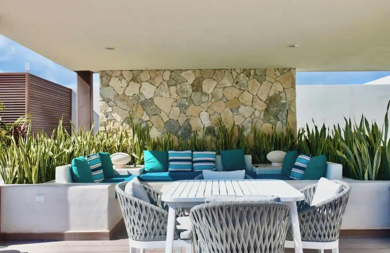 An outdoor patio with a stone wall, seating area, and a table.