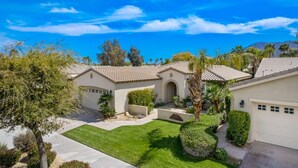 A residential property with a well-maintained lawn, a garage, and a patio area.