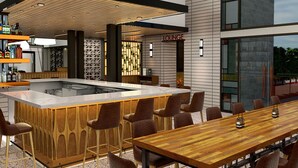 A modern bar/lounge area with a wooden bar counter, seating, and a large window overlooking the city.