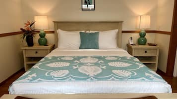 A neatly made bed with a floral bedspread, two bedside tables with lamps, and a framed picture on the wall.