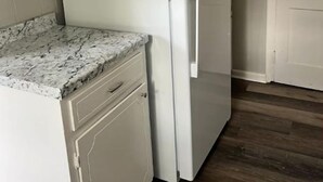 A kitchen with a white refrigerator, a marble countertop, and wooden flooring. - Cozy & Quite 2BR 1Bath Duplex Private Entrance Perfect for work Stays (Valdosta)