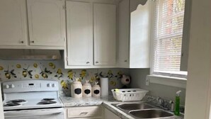 A compact kitchen with white cabinets, a built-in oven, a sink, and a window with blinds. - Cozy & Quite 2BR 1Bath Duplex Private Entrance Perfect for work Stays (Valdosta)