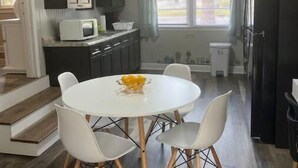 A modern kitchen with a white table and chairs, a microwave, and a refrigerator.