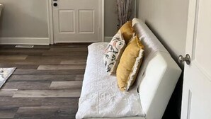 Una habitación con un sofá blanco, una puerta y un cuadro en la pared.