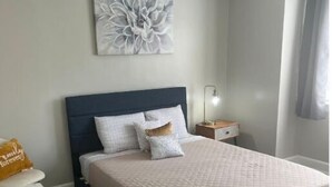 Un dormitorio con cama, mesita de noche, lámpara y ventilador de techo.