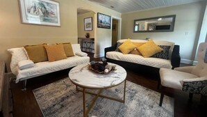 A living room with two sofas, a coffee table, and a chair. There are framed pictures on the walls. - Peaceful Private home near VSU, Down town & SGMC (Valdosta)