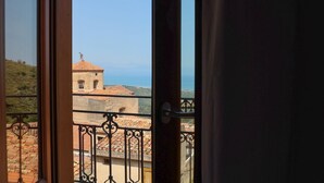 A balcony with a view of a building with a tiled roof and a statue on top. - Le Signorine Panoramic apts: Donna Rosina (Gratteri)
