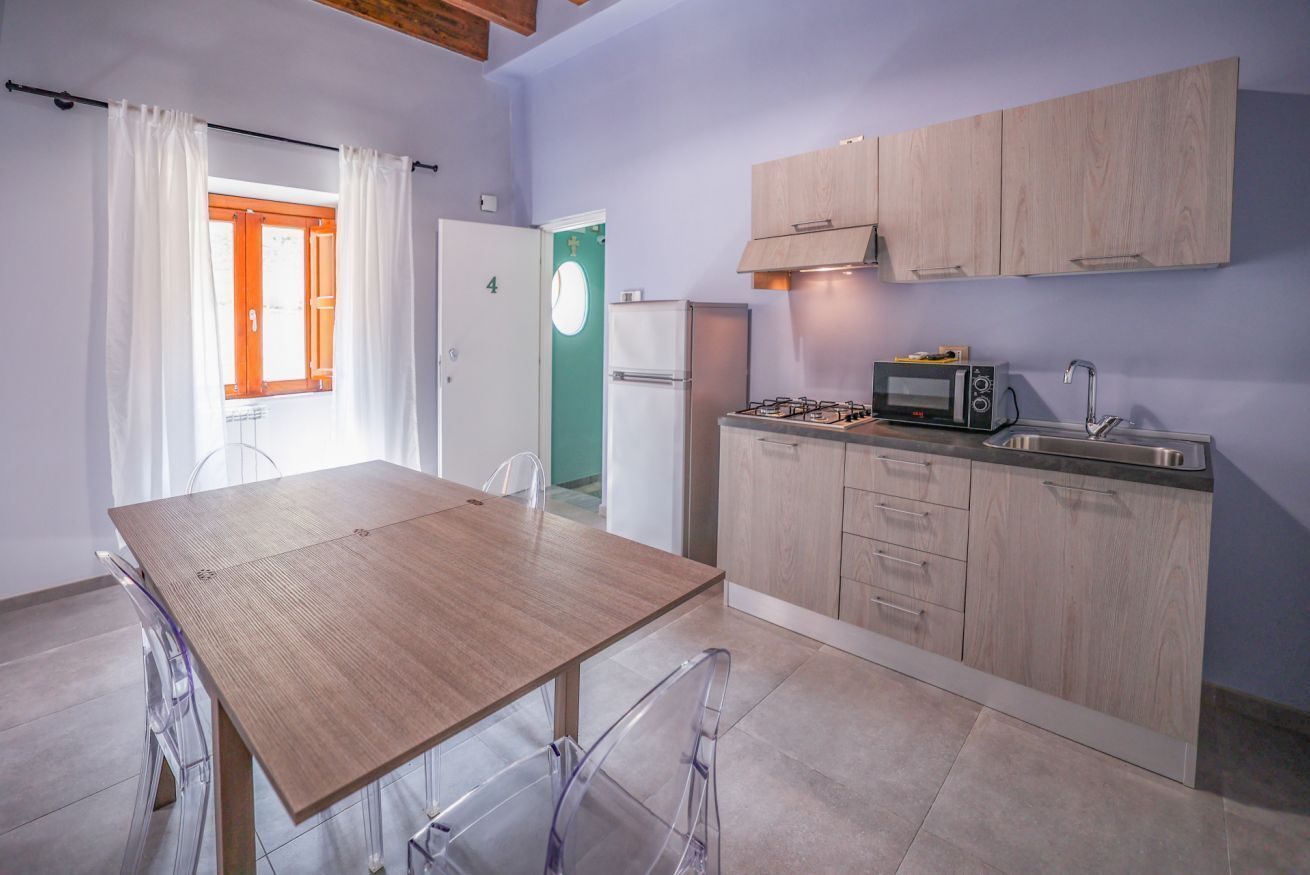 Una cucina compatta con tavolo e sedie in legno, un forno a microonde e un lavandino.