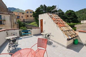 Eine Dachterrasse mit Sitzgelegenheiten im Freien, einer Tür und einer Satellitenschüssel.