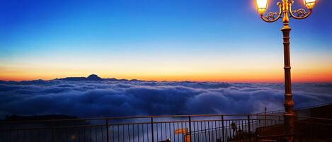 A bench and a lamp post overlooking a sea of clouds.