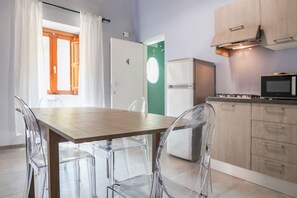 Eine moderne Küche mit Holztisch und transparenten Stühlen, einem Kühlschrank, einer Mikrowelle und Holzschränken.