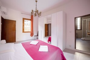 A hotel room with a bed, a large mirror, a wardrobe, and a bathroom visible through a glass door.
