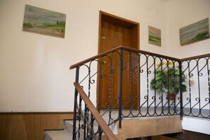 A wooden staircase with a metal railing, a wooden door, and three landscape paintings on the walls. - Ca Soranzo, next to the Biennale (Venezia)