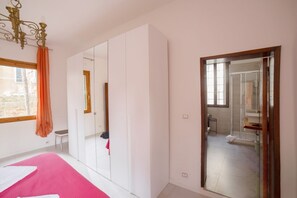 A bedroom with a bed, wardrobe, and a bathroom visible through a glass door.