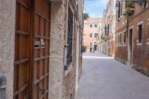 A narrow street with buildings on either side, featuring wooden doors and windows. - Ca Soranzo, next to the Biennale (Venezia)