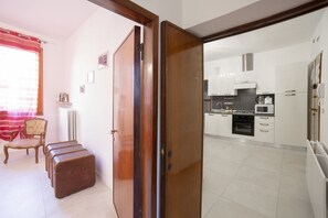 Une cuisine moderne avec des armoires blanches, une cuisinière et un four à micro-ondes. Une porte en bois donne accès à une autre pièce, et on aperçoit une chaise au premier plan.