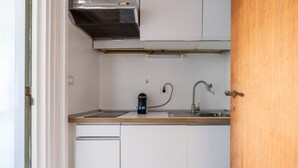A compact kitchen with white cabinets, a stainless steel sink, and a built-in range hood.