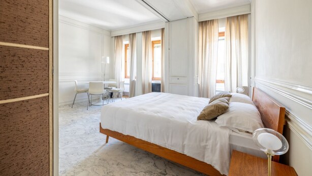 A hotel room with a large bed, a desk, and a chair.