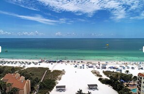 A beach view with a clear sky, a sandy beach, and a few umbrellas.