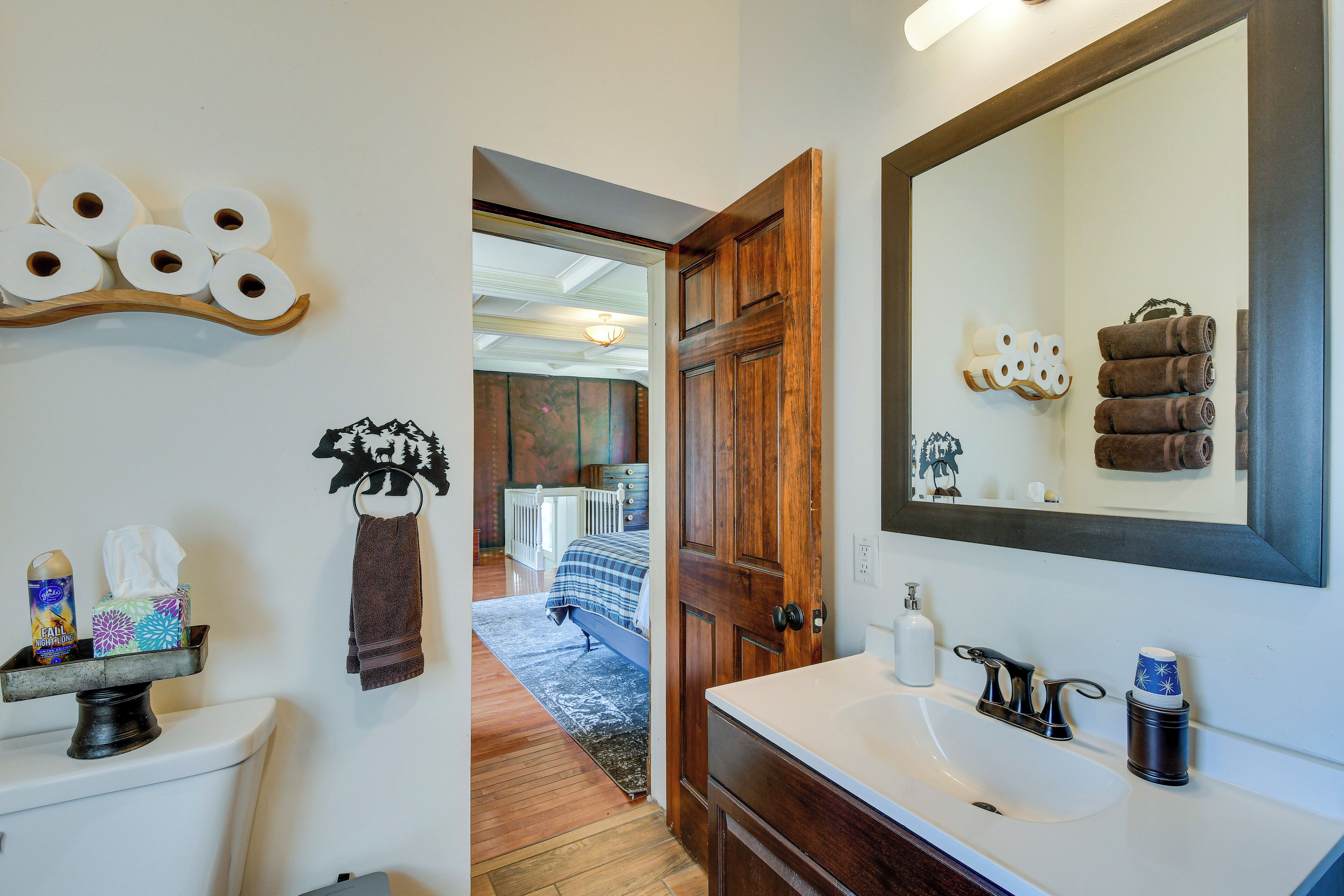 A bathroom with a wooden door, a large mirror, and a sink.