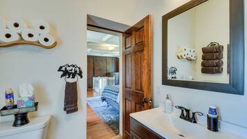 A bathroom with a wooden door, a large mirror, and a sink.