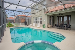 Piscina interna com espreguiçadeiras, uma mesa e cadeiras.