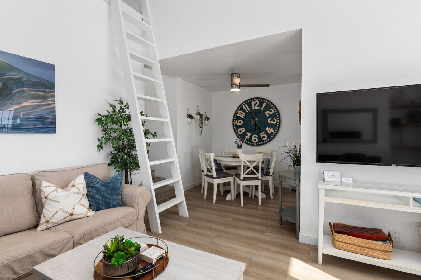 Een moderne woonkamer met een bank, salontafel, televisie en een eethoek met tafel en stoelen.