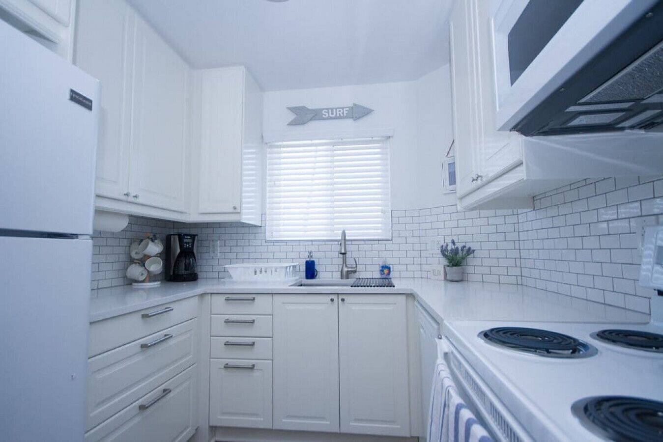 Une cuisine moderne avec des meubles blancs, une cuisinière et un évier.