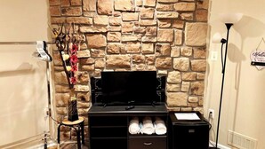 A room with a stone wall, a black entertainment unit with storage, a small stool with a vase, and a sign on the wall. - Room in House - The Modern Gem Furnished Bedroom (Alexandria)