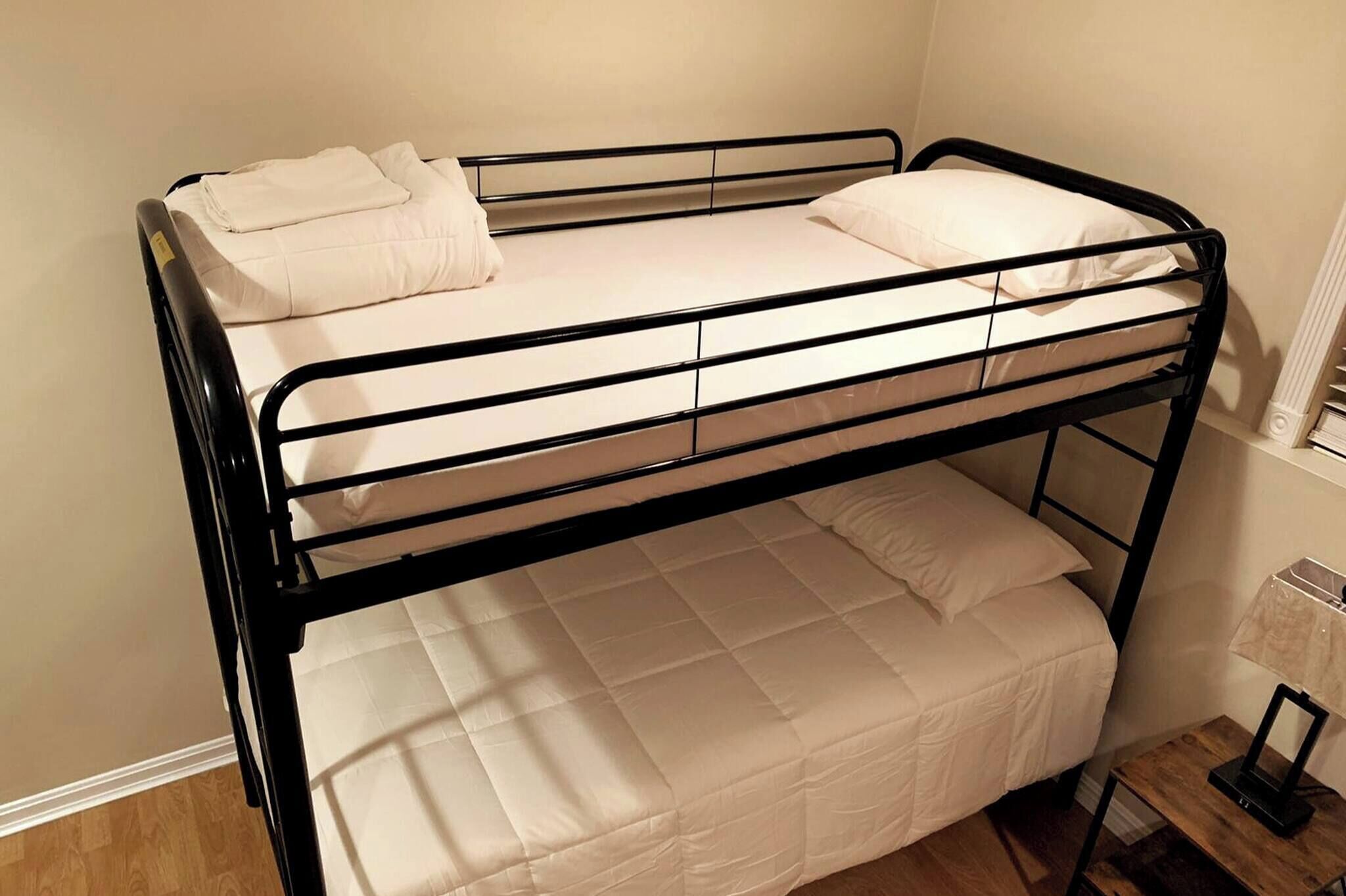 A bunk bed with two levels, each with a mattress and pillows.