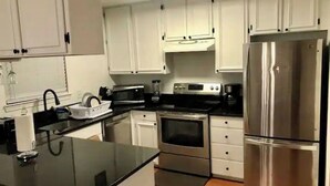 A modern kitchen with white cabinets, stainless steel appliances, and a black countertop. - Room in House - The Modern Gem Furnished Bedroom (Alexandria)