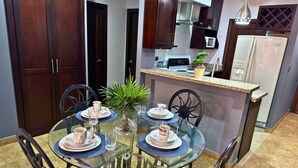 A dining area with a glass table, four chairs, and a small potted plant. - Apartamentos Casa del Valle (San Pedro Sula)