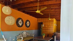 A room with a hammock, wicker furniture, a ceiling fan, and decorative wall art. - Apartamentos Casa del Valle (San Pedro Sula)
