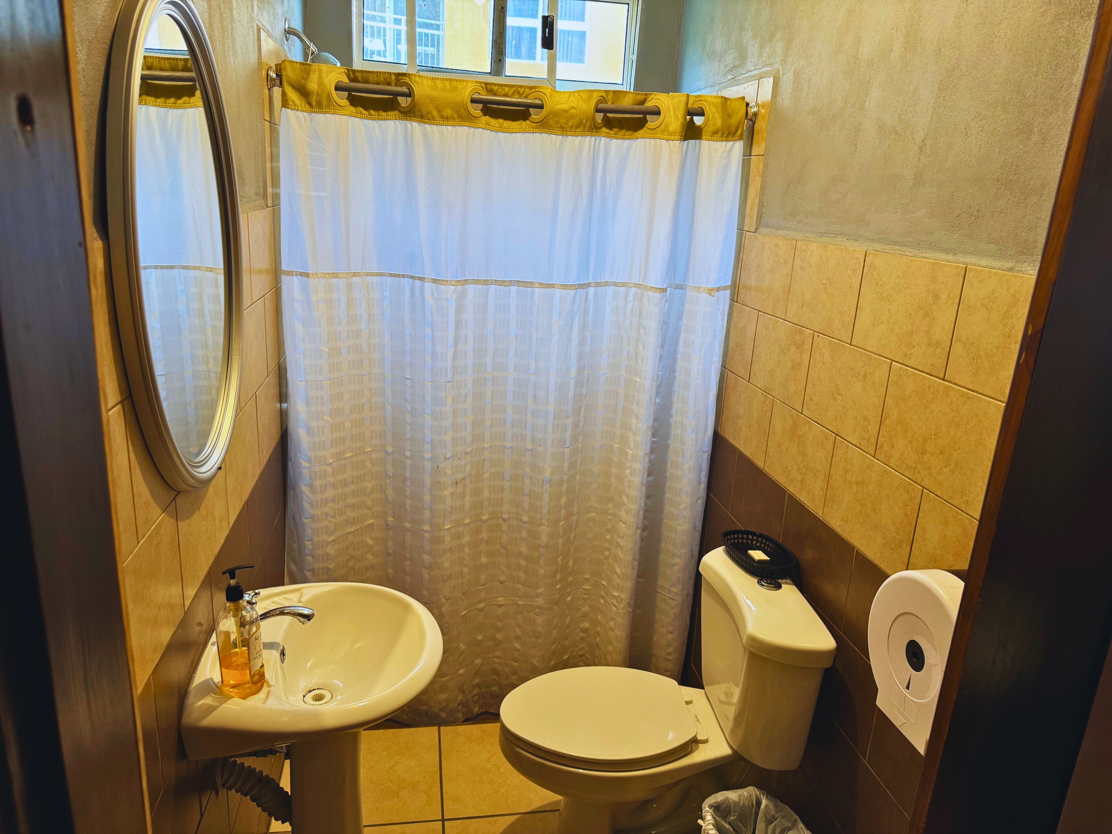 Un baño pequeño con lavamanos, inodoro y cortina de ducha.