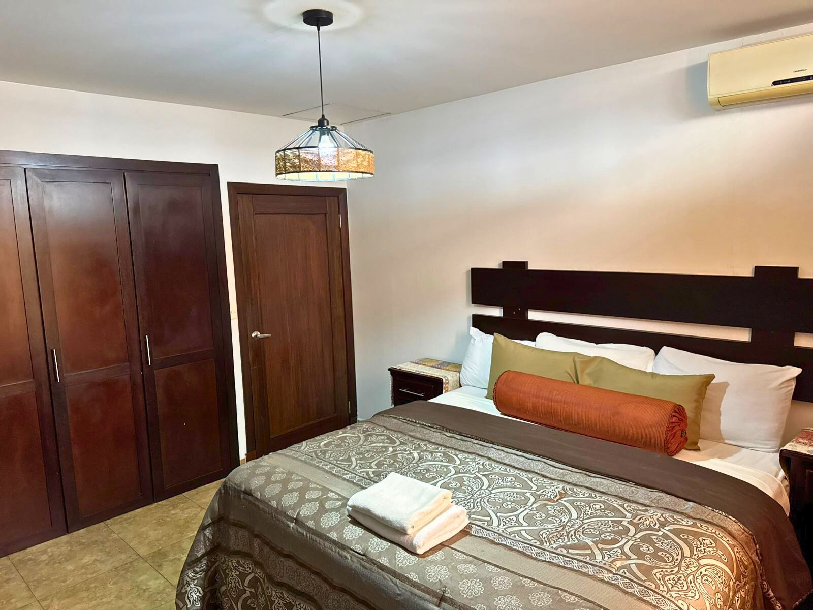 A hotel room with a bed, a wardrobe, a nightstand, and a ceiling fan.