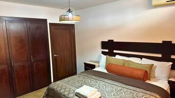 A hotel room with a bed, a wardrobe, a nightstand, and a ceiling fan.