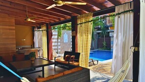 A covered outdoor seating area with a pool, wooden ceiling, and a hammock. - Apartamentos Casa del Valle (San Pedro Sula)