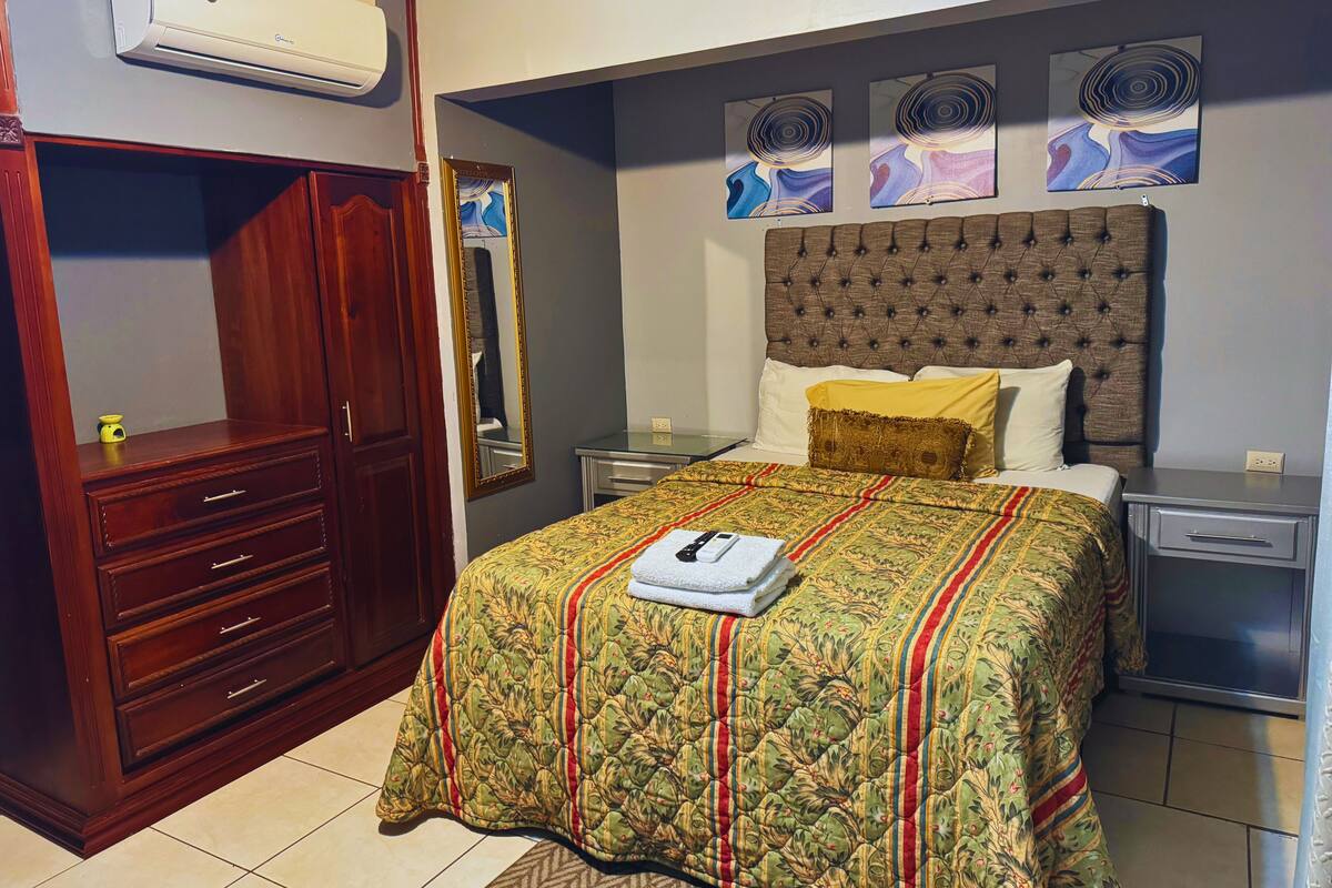 Une chambre à coucher comprenant un lit, une armoire, un miroir et des œuvres d’art accrochées au mur.