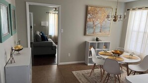 Un comedor con una mesa dispuesta para cuatro personas, un armario blanco y un cuadro en la pared.