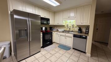 A kitchen with white cabinets, stainless steel appliances, and a tiled floor.