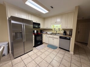 A kitchen with white cabinets, stainless steel appliances, and a tiled floor.